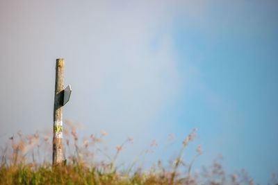 Low angle view of wooden post on field against sky