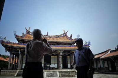 Senior men standing in temple against clear sky