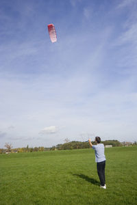 Man with paragliding on grassy field against sky during sunny day