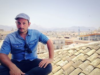 Portrait of young man sitting against sky