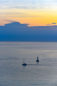 Sailboat sailing on sea against sky during sunset