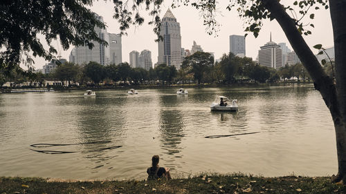 People swimming in lake with city in background