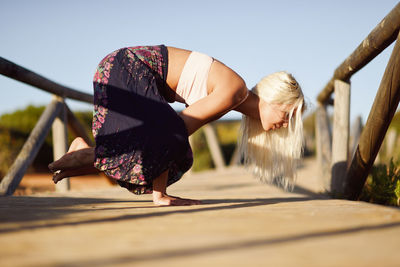 Young woman exercising while standing on footbridge