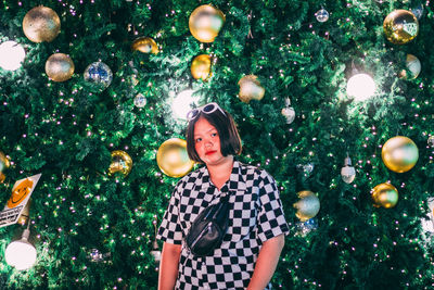 Low angle view of young woman standing by tree