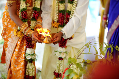 Midsection of couple holding diya during wedding ceremony