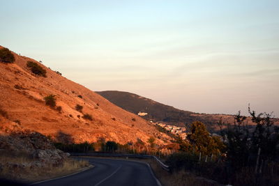 Scenic view of road by mountains against sky