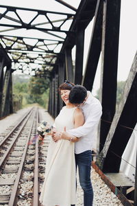 Rear view of man and woman standing on railroad track