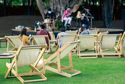 Many white deck chairs with tables for dinner in lawn is surrounded by shady green grass 