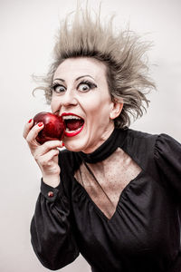 Portrait of woman with apple against white background