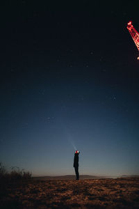 Man standing on field against sky at night