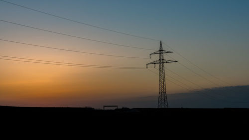 Silhouette of power lines against sunset sky
