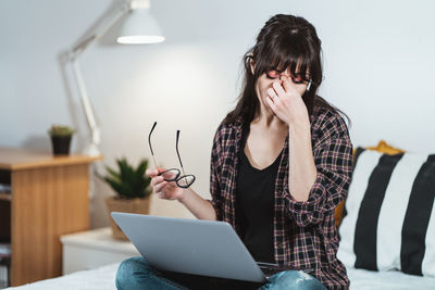 Exhausted businesswoman sitting on bed at home