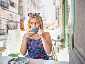 Young woman drinking coffee while sitting at cafe