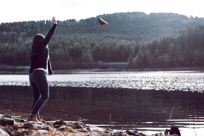 Side view of woman throwing stone in lake