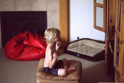 Side view of shirtless boy meditating at home