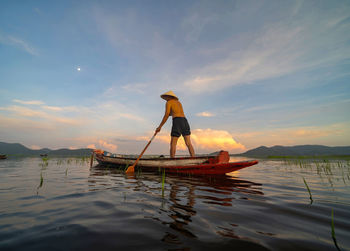 Fishing boat in sea against sky during sunset