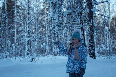 Portrait of girl standing in snow covered forest