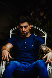 Young man looking away while sitting on chair