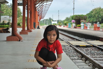 Portrait of girl crouching on railroad station platform