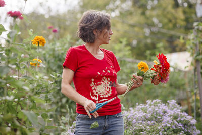 A woman stands with a bouquet of wildflowers in a beautiful garden