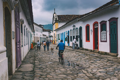 Man riding bicycle on footpath amidst houses