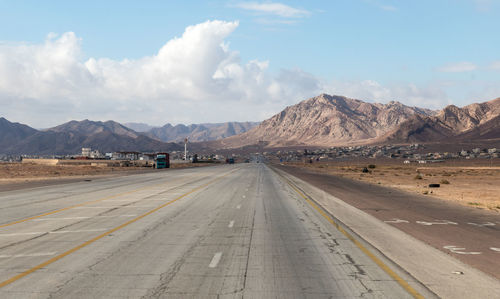 Road by mountains against sky