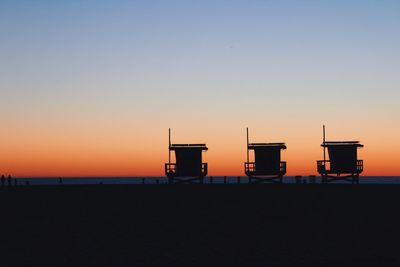 Silhouette beach against clear sky during sunset