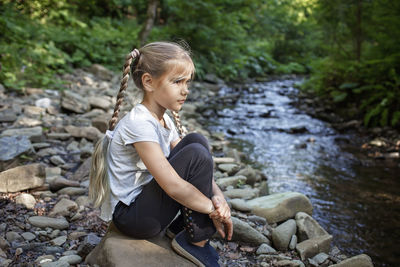 Full length of woman sitting on rock