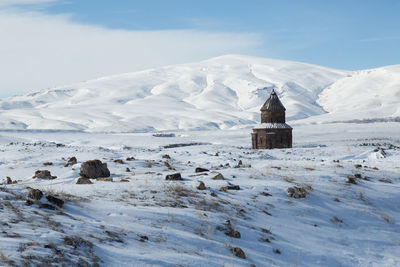 House on snow covered mountains against sky