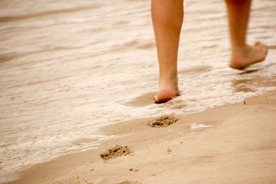 Low section of man standing on beach