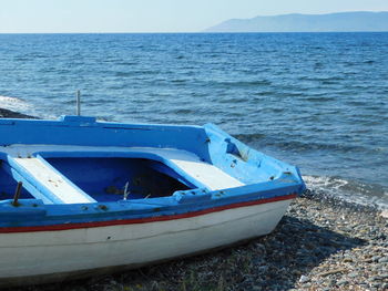 Boat moored on sea shore against sky