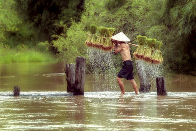 Full length of woman standing by river in park