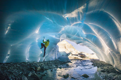 Man ice climbing in ice cave during luxury adventure tour.