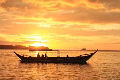 Silhouette boats in sea against orange sky