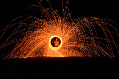 Young man spinning wire wool at night