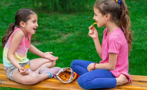 Side view of mother and daughter sitting at park