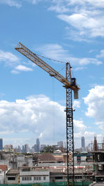 Cranes at construction site against sky in city