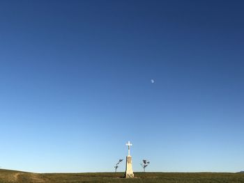 Low angle view of wind turbines on field against clear blue sky