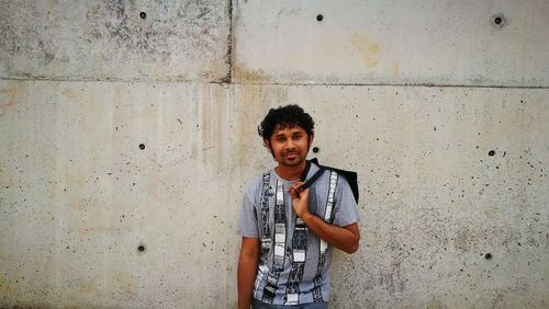 Portrait of smiling man standing against wall