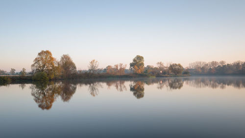 Scenic view of lake against clear sky during sunset