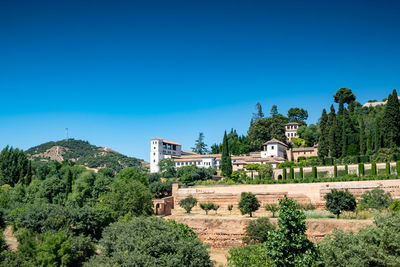 Built structure by trees against blue sky