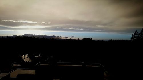 Silhouette of trees against cloudy sky