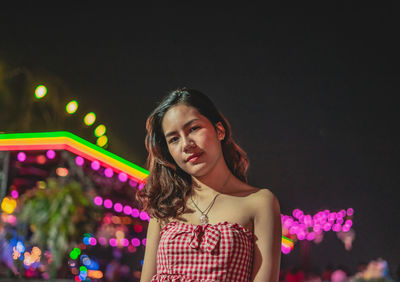 Portrait of a beautiful young woman standing at night