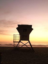Lifeguard hut on beach against sky during sunset