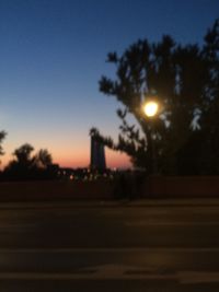 Defocused image of illuminated road against sky at night