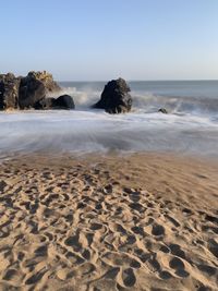 Scenic view of rocks on beach against sky