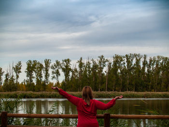 Rear view of woman looking at lake against trees