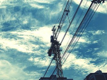 Low angle view of electricity pylon against cloudy sky