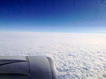 Airplane flying over cloudscape against blue sky