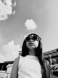 Portrait of young woman wearing sunglasses standing against sky